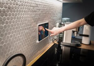 Residents adjust smart lighting and climate controls in a bright home living room with sensors and motorized shades.