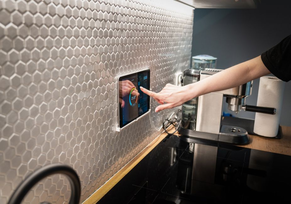 Residents adjust smart lighting and climate controls in a bright home living room with sensors and motorized shades.